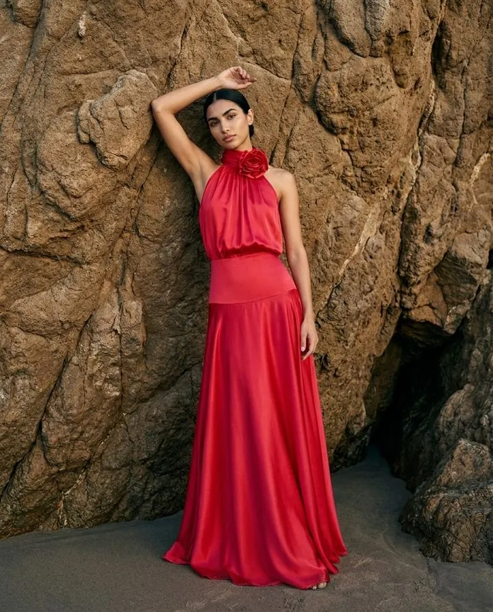 Red satin halter gown with a rosette against a sandstone cliff